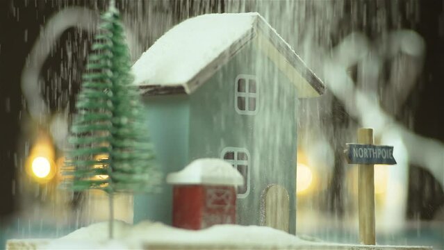 Christmas house model with new year tree rotation on warm lights garland background under heavy imitation snow falling. Kids Dreams Closeup Indoors. Festive Magic, Christmas Spirit