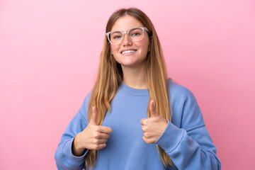 Young blonde woman isolated on pink background With glasses and with thumb up