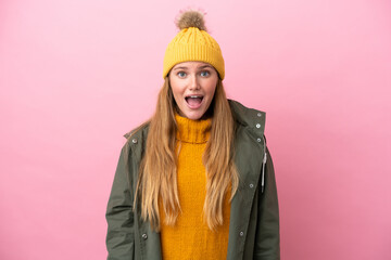 Young blonde woman wearing winter jacket isolated on pink background with surprise facial expression