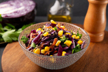  Fresh salad with red cabbage, carrots, hemp seeds and corn in a bowl on the table