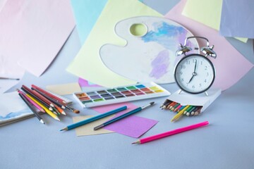 Back to school, watercolor paints, brushes and colored pencils, palette, school supplies on a gray background
