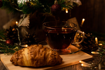 Cup of tea with croissant near Christmas tree.New Year's Eve at home with family