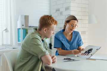 Teenager taking Rorschach test during psychological therapy with adolescent psychologist. Psychological session for teenage boy. Concept of teen mental health and unique adolescent behaviour, problems