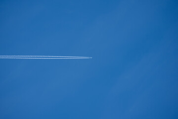 Airplane flying in clear blue sky leaving contrail. Background with space for text.