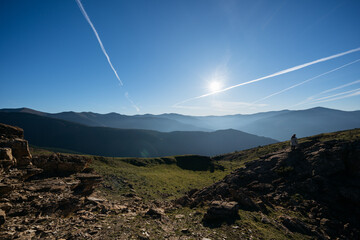 Beautiful scenery with mountains and airplanes' contrails on clear blue sky. © Maria
