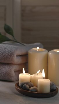 Beauty spa treatment items on white wooden table. Candles, stones and towels. Cozy bath.