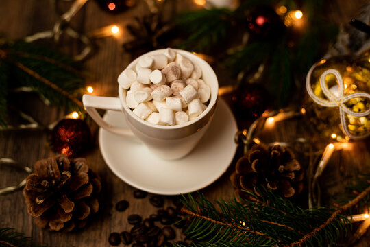 Marshmelon in a white cup on a table with Christmas lights. Christmas tree