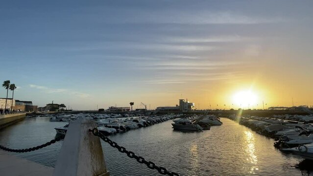 Por do sol na ba&iacute;a de Faro - Portugal. Com uma doca e barcos ao fundo - Novembro-2023