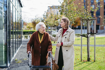 Granddaughter helping her grandmother to fill her prescription medications. Senior woman with a mobility walker and her caregiver leaving pharmacy.