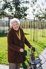 Senior woman with a mobility walker walking on city streets during autumn day, enjoying the...