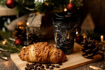 Coffee to go and croissant near the Christmas tree. New Year's Eve Sweets