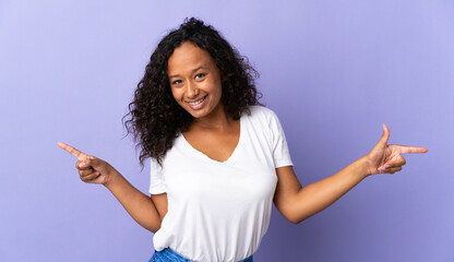 Teenager cuban girl isolated on purple background pointing finger to the laterals and happy