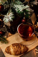 Cup of tea with croissant near Christmas tree.New Year's Eve at home with family