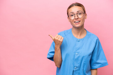 Young nurse doctor woman isolated on pink background pointing to the side to present a product