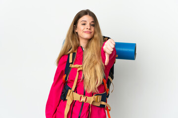 Young mountaineer woman with a big backpack over isolated background showing thumb down with negative expression