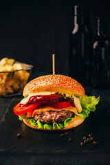 close-up of a hamburger on a black table with fries in the background