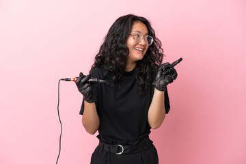 Tattoo artist asian woman isolated on pink background intending to realizes the solution while lifting a finger up - obrazy, fototapety, plakaty