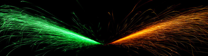 red and green fast-flying sparks from angle grinders on black background