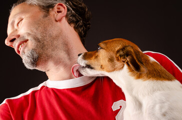Cute young Jack Russell Terrier giving kisses on the arm of his human friend