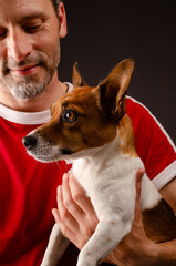 Cute young Jack Russell Terrier on the arm of his human friend