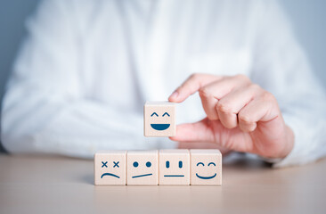 Hand chooses smiley happy face on wooden cube from normal and sad emotion on others. World Mental...