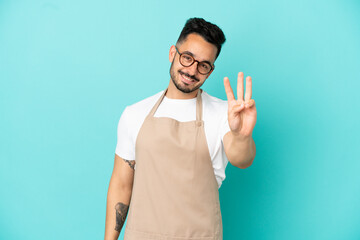 Restaurant waiter caucasian man isolated on blue background happy and counting three with fingers
