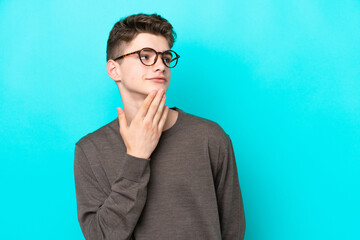 Teenager Russian man isolated on blue background looking up while smiling