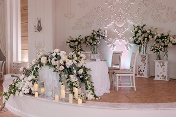 Wedding ceremony. Presidium for the newlyweds, decorated with candles and vases with white natural flowers such as eustoma, hydrangea, roses. Floristic concept