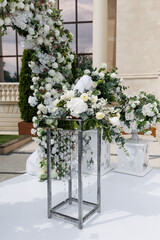 Close up of a table decorated with fresh white and yellow flowers for painting the newlyweds against the backdrop of the arch. Wedding concept