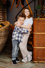 Obraz premium Little brother and sister hugging in the interior of a country house.