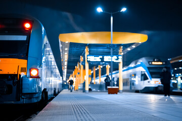 Passenger railway transport, a modern train at the station standing on the platform. Perspective view of a platform with trains at night.