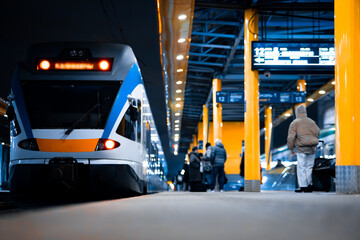 Passenger railway transport, a modern train at the station standing on the platform. Perspective view of a platform with trains at night.
