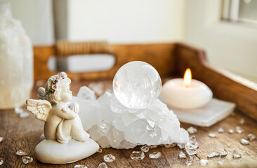 Spiritual angel message concept. Small cute angel figurine sit by crystal gemstone ball in home...