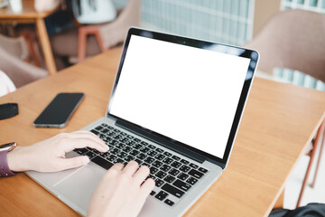 Mockup image of a woman using laptop with blank white screen on wooden table in modern loft cafe