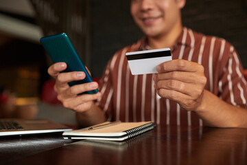 Cropped image of smiling man paying with credit card when shopping in mobile application