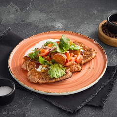 Breaded pork cutlets topped with a fresh and vibrant vegetable salad, artistically served on a...