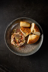 A vertical top view of hummus accompanied by Uzbek tandoor bread, beautifully presented on a dark ceramic plate
