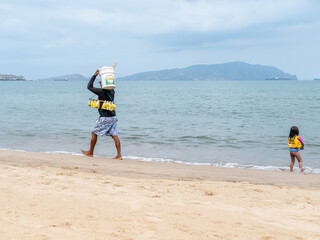 street vendor on the beach, Street vendor walking and selling various types of food on the beach