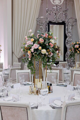 Wedding decorations. Served wedding table with decorative fresh white and pink flowers, candles. Celebration details. Flower composition roses, plates, candles in candlesticks 