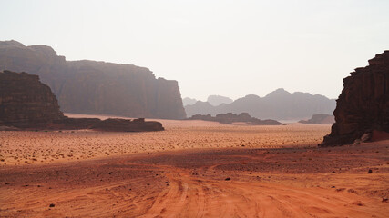 Desert vista point with towering sandstone cliffs and orange sands road. Wadi Rum desert, Jordan.