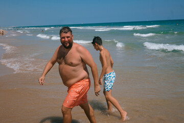 Fototapeta na wymiar Teenage boy and an adult man enjoying a fabulous day at the beach.
