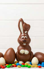 Easter chocolate bunny on a light texture table. Chocolate eggs and other sweets. Easter celebration concept. Easter sweets on the table. Place for text. copy space.