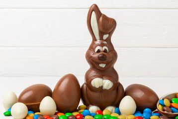 Easter chocolate bunny on a light texture table. Chocolate eggs and other sweets. Easter celebration concept. Easter sweets on the table. Place for text. copy space.