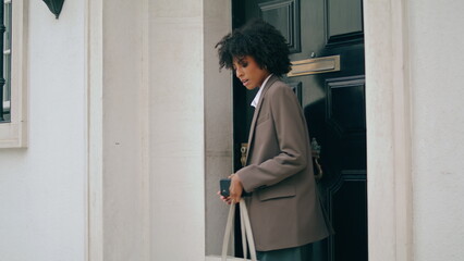 Business woman leaving house closing door closeup. Lady going outdoors in suit.