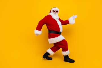 Fototapeta na wymiar Full length profile portrait of positive santa walking empty space new year offer isolated on yellow color background