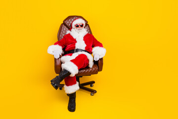 Fototapeta na wymiar Happy new year concept photo of santa claus in boss armchair wear cool sunglasses relaxed red costume isolated on yellow color background