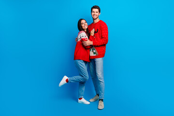 Full body photo of attractive young couple embrace dating lovers wear x-mas ornament red sweaters isolated on blue color background - obrazy, fototapety, plakaty