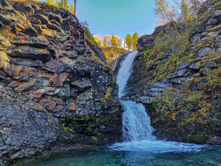 A beautiful waterfall in the autumn mountains beyond the Arctic Circle in the north, in Khibiny,...