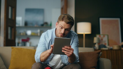 Surprised businessman looking pad screen sitting sofa. Wondering guy reading tab - Powered by Adobe