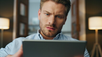 Focused man reading pad computer zoom out. Serious businessman zooming screen